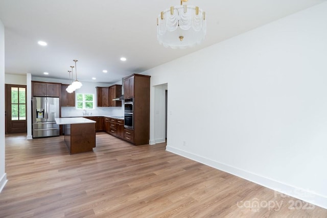 kitchen featuring dark brown cabinetry, a kitchen island, light wood-style floors, light countertops, and appliances with stainless steel finishes