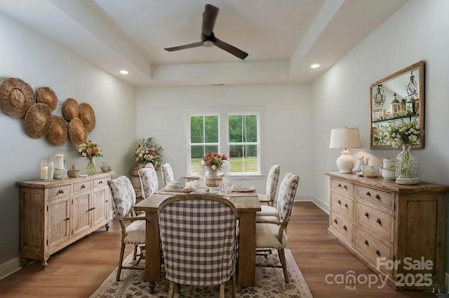 dining room with a raised ceiling, ceiling fan, recessed lighting, and wood finished floors