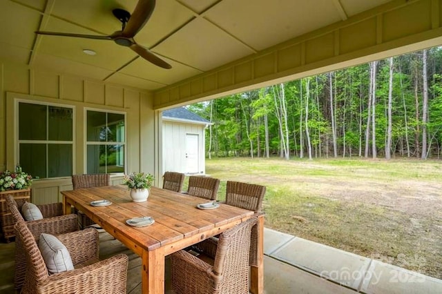 view of patio with outdoor dining area, ceiling fan, and a forest view