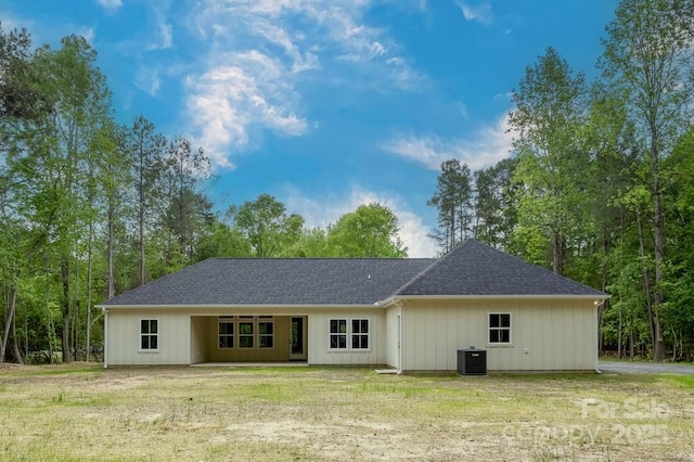 back of property with a shingled roof, a yard, and cooling unit