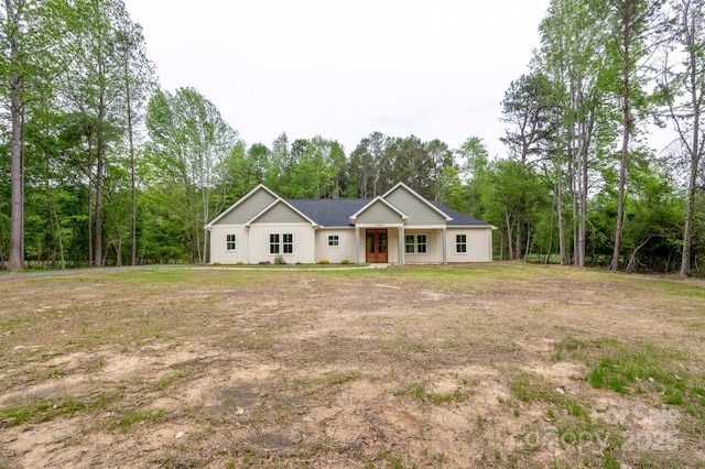 ranch-style house featuring a front lawn, board and batten siding, and french doors