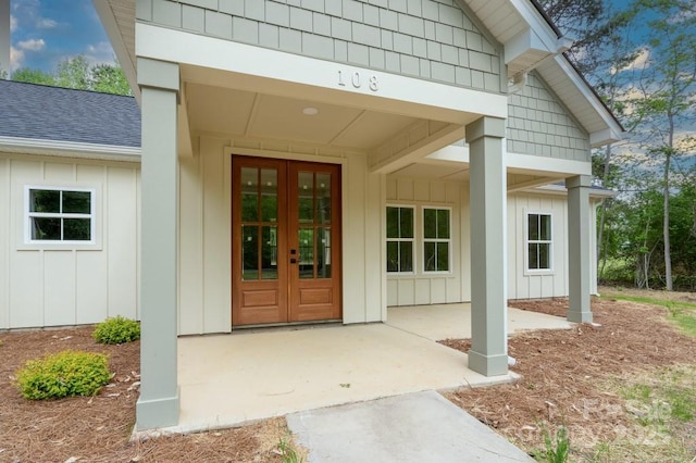 view of exterior entry with board and batten siding, french doors, and a shingled roof