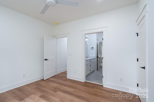 unfurnished bedroom featuring baseboards, light wood-style flooring, and ensuite bathroom