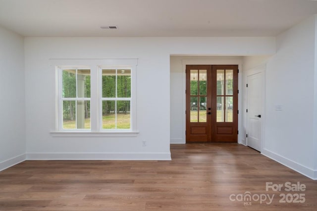 entrance foyer with baseboards, french doors, wood finished floors, and visible vents