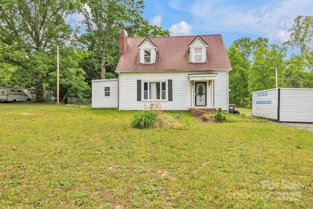 cape cod house with metal roof, a chimney, and a front lawn
