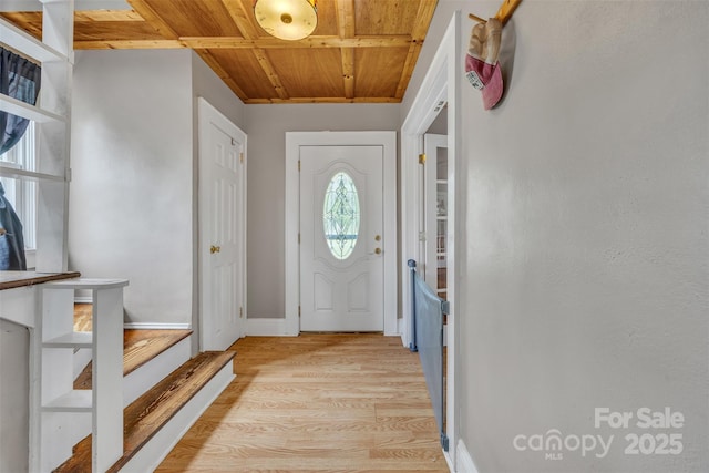 doorway with baseboards, wooden ceiling, light wood-style flooring, and plenty of natural light