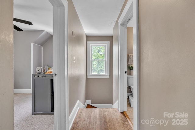 hallway with baseboards, carpet flooring, and an upstairs landing