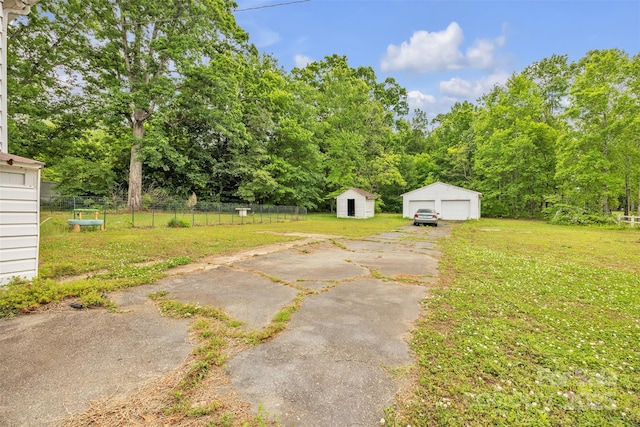 view of yard with a garage, fence, and an outbuilding