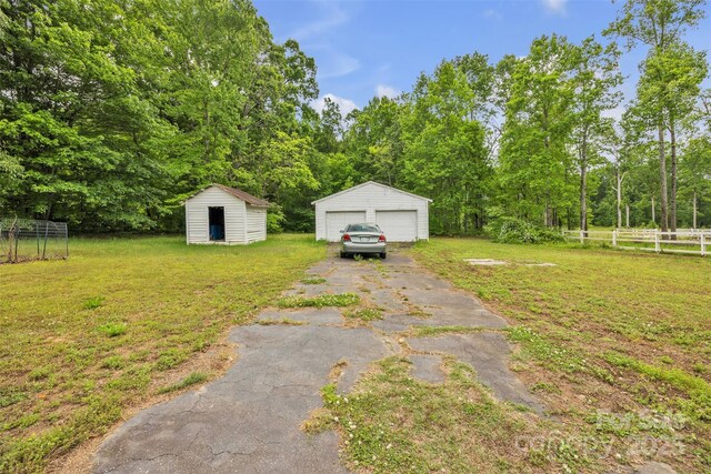 view of yard with a garage, fence, an outbuilding, and a storage unit
