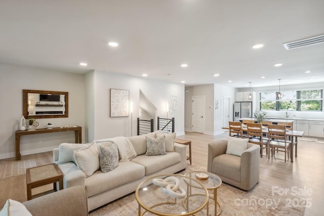 living area with recessed lighting, light wood finished floors, stairs, and baseboards