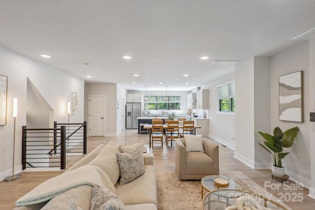 living area featuring light wood finished floors, baseboards, and recessed lighting