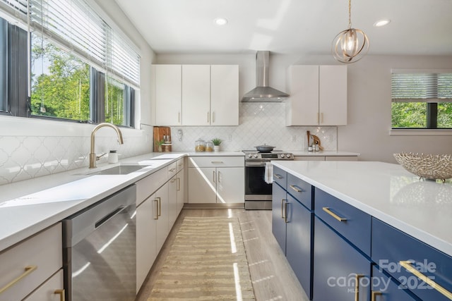 kitchen with stainless steel appliances, wall chimney exhaust hood, a sink, plenty of natural light, and recessed lighting
