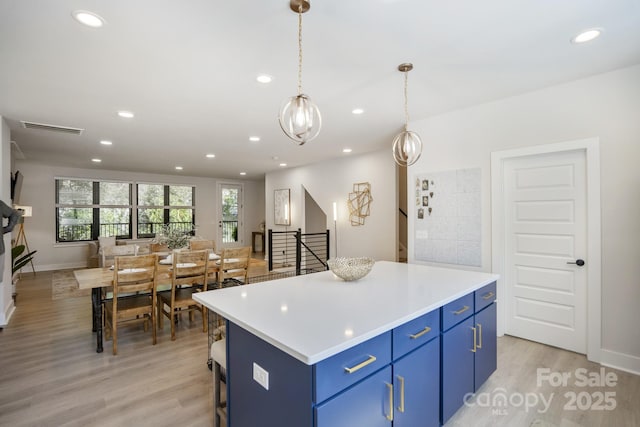 kitchen with blue cabinetry, light wood-style floors, recessed lighting, a center island, and light countertops