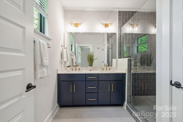 full bath featuring a stall shower, double vanity, tile patterned flooring, and baseboards