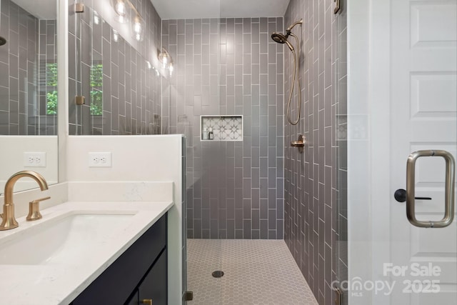 full bath featuring tiled shower and vanity