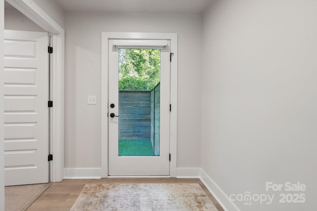 doorway featuring light wood-type flooring and baseboards