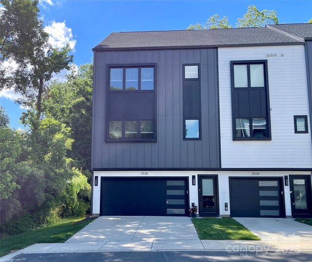 contemporary home with an attached garage, concrete driveway, and a shingled roof
