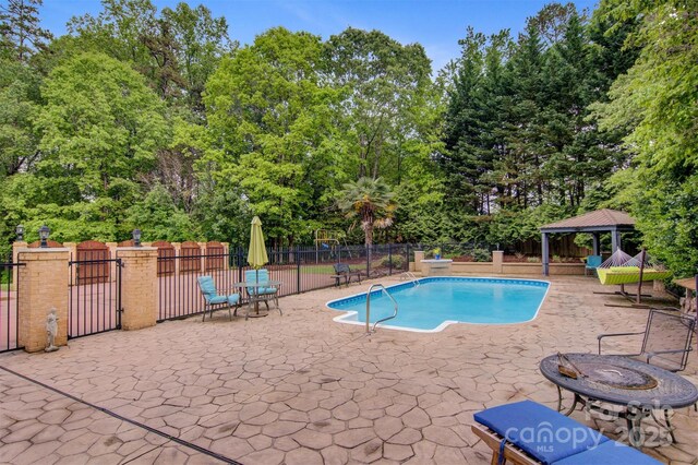 view of swimming pool with a gazebo, a patio area, fence, and a fenced in pool