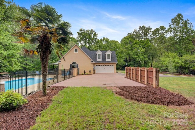 view of side of home featuring fence, a garage, a fenced in pool, concrete driveway, and a lawn