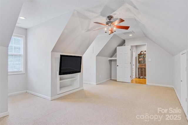 additional living space featuring a ceiling fan, visible vents, carpet floors, baseboards, and lofted ceiling