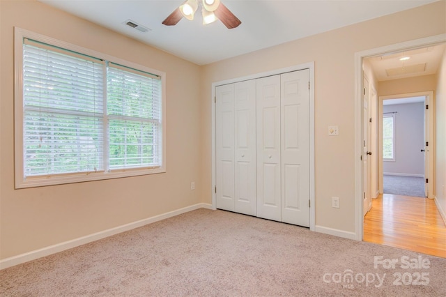 unfurnished bedroom with attic access, visible vents, baseboards, a closet, and carpet flooring