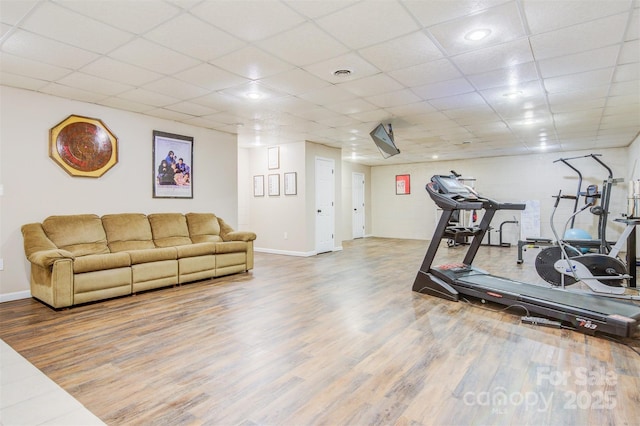 exercise area featuring baseboards, visible vents, a drop ceiling, and wood finished floors