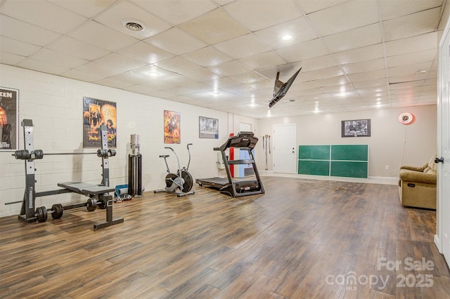 workout room featuring concrete block wall, baseboards, visible vents, and wood finished floors