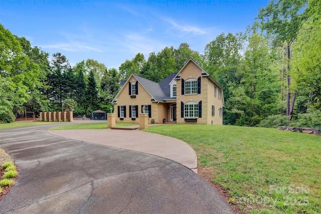 traditional home with a front lawn and aphalt driveway