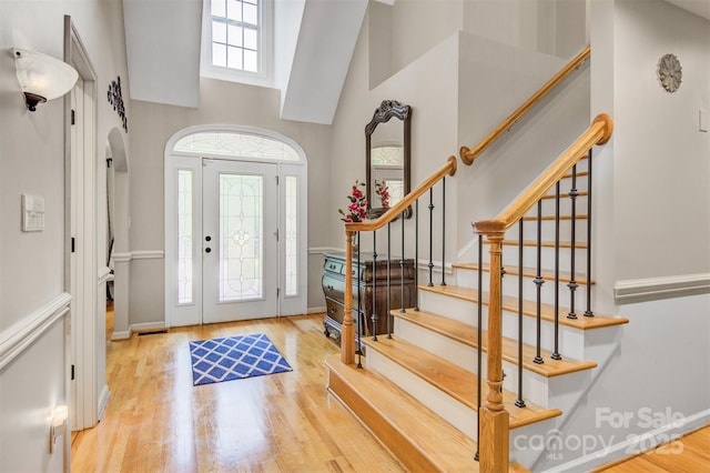 foyer entrance with a high ceiling, wood finished floors, and stairway