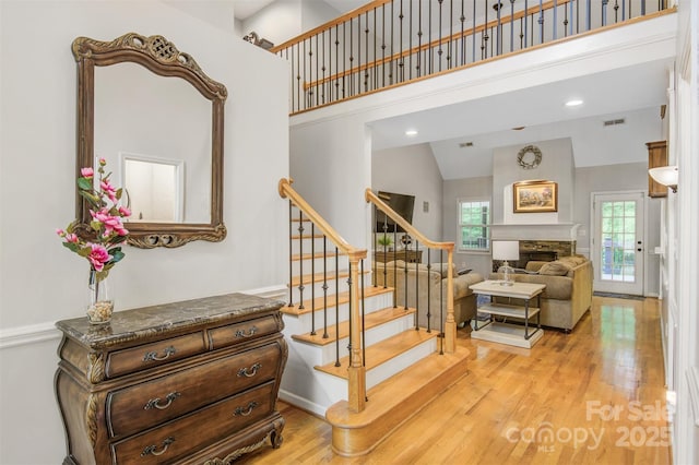 stairway with visible vents, wood finished floors, a fireplace, baseboards, and a high ceiling