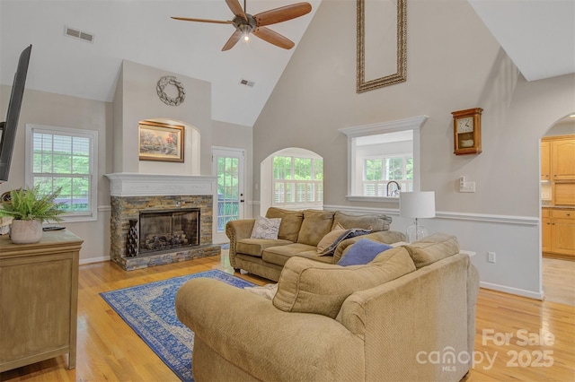 living area with high vaulted ceiling, ceiling fan, arched walkways, and visible vents