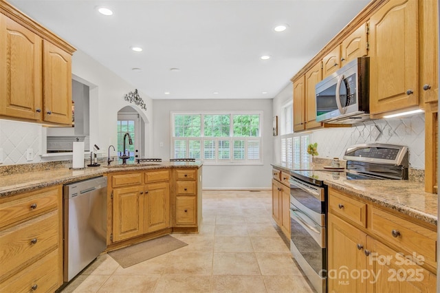 kitchen featuring light stone countertops, recessed lighting, tasteful backsplash, a sink, and stainless steel appliances