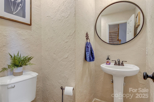 bathroom with a textured wall and toilet