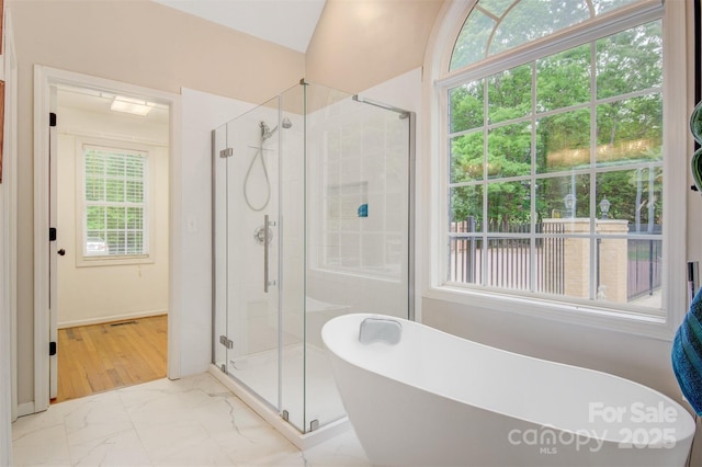 bathroom featuring baseboards, a stall shower, marble finish floor, and a freestanding bath