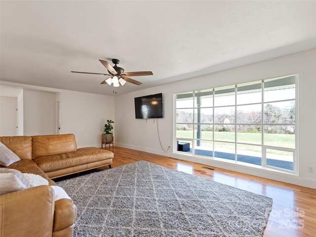 living room with light wood finished floors, ceiling fan, and baseboards