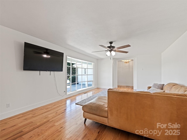 living room featuring wood finished floors, ceiling fan, and baseboards