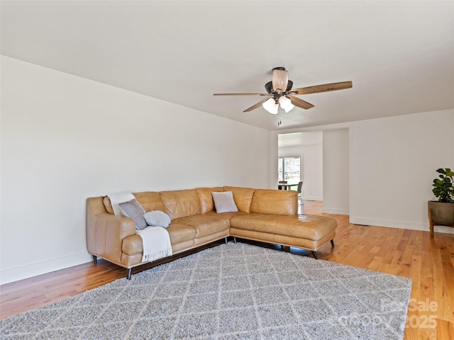living area with ceiling fan, baseboards, and light wood-type flooring