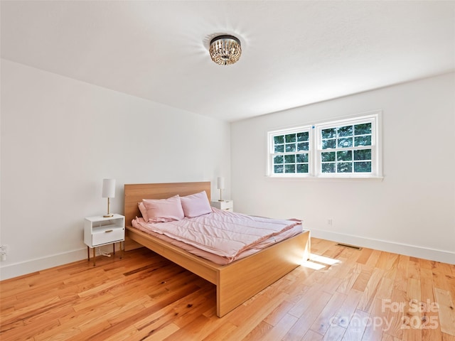 bedroom with visible vents, wood finished floors, and baseboards