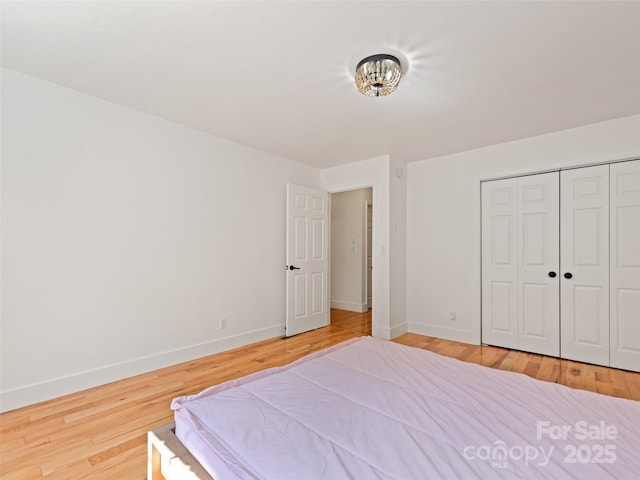 bedroom with wood finished floors, a closet, and baseboards