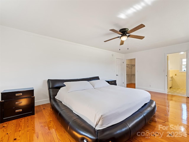 bedroom featuring baseboards, ceiling fan, light wood-style floors, and connected bathroom