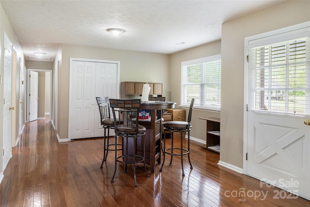 dining area featuring baseboards, a textured ceiling, dark wood-style flooring, and attic access