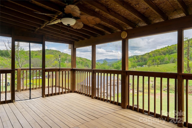 unfurnished sunroom featuring a ceiling fan and a mountain view