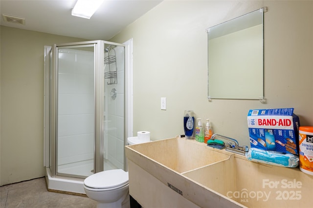 bathroom featuring toilet, visible vents, a sink, and a stall shower
