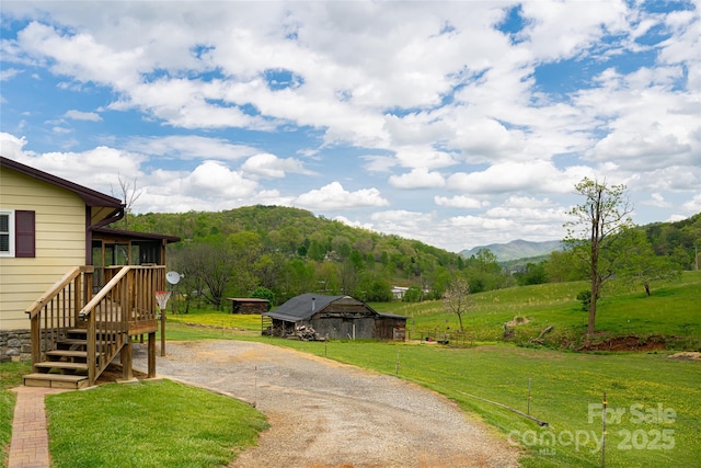 view of yard with driveway, a sunroom, a mountain view, a rural view, and stairs
