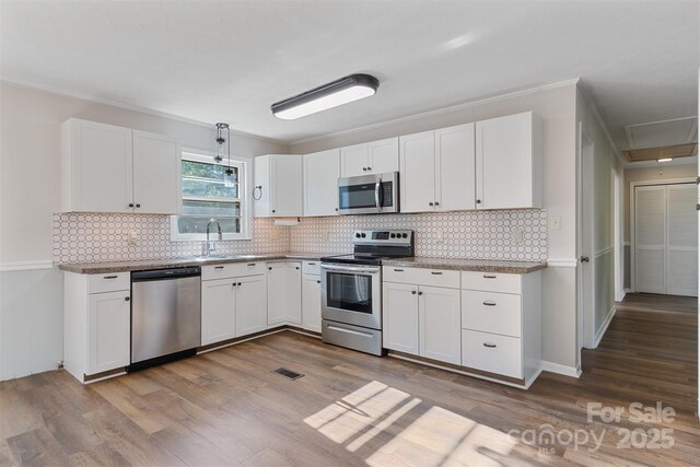 kitchen featuring stainless steel appliances, white cabinetry, wood finished floors, and visible vents