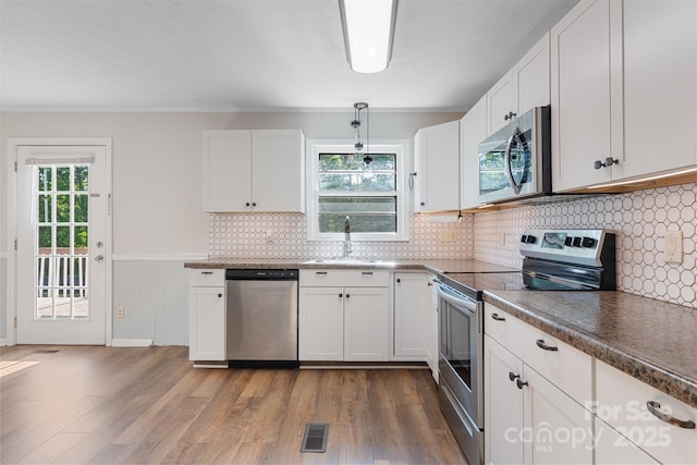 kitchen with white cabinetry, appliances with stainless steel finishes, a sink, and visible vents