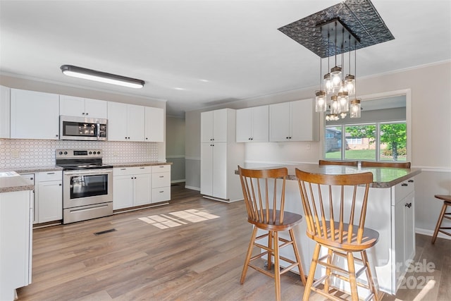 kitchen with light wood-style floors, a kitchen breakfast bar, backsplash, and stainless steel appliances
