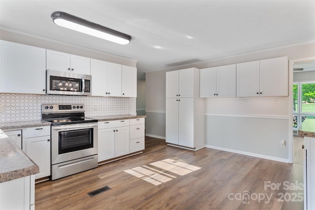 kitchen featuring white cabinets, appliances with stainless steel finishes, and decorative backsplash