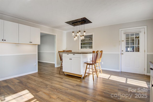 dining space with crown molding, baseboards, and wood finished floors