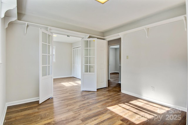spare room with baseboards and wood finished floors